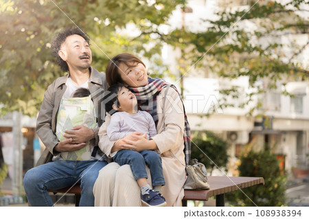 A family of four looking up at the sky in a park with autumn leaves A family of four looking up at the sky in a park with autumn leaves 108938394