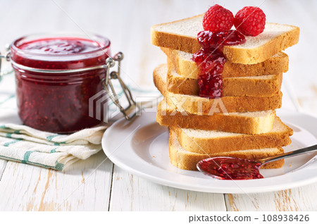 A stack of toast with raspberry jam on a dish close-up. Plate with pieces of toasted bread and tasty raspberry jam. A stack of toast with raspberry jam on a dish close-up. Plate with pieces of toasted bread and tasty raspberry jam. 108938426