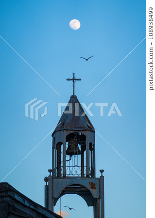 From below of bird flying over old bell tower against clear blue sky with moon at twilight in Istanbul, Turkey From below of bird flying over old bell tower against clear blue sky with moon at twilight in Istanbul, Turkey 108938499