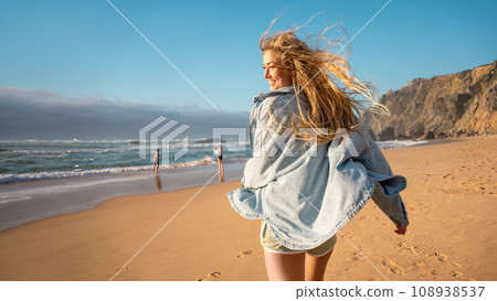 Woman running beach and smiling for camera Woman running beach and smiling for camera 108938537
