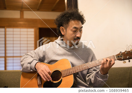 A man playing an acoustic guitar 108939465