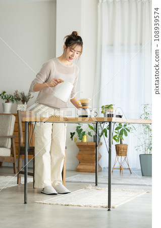 A woman making coffee in her room A woman making coffee in her room 108939574