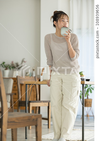 A woman who drinks coffee in a room A woman who drinks coffee in a room 108939656