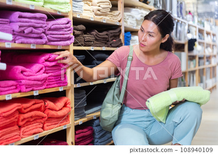 Contented woman choosing toilet towels in textile store closeup Contented woman choosing toilet towels in textile store closeup 108940109