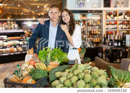 Portrait of a happy young couple with products in a cart in the supermarket Portrait of a happy young couple with products in a cart in the supermarket 108940188