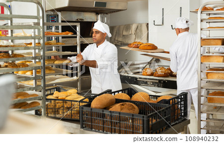 male baker with bread in baking shovel and cart in kitchen male baker with bread in baking shovel and cart in kitchen 108940232