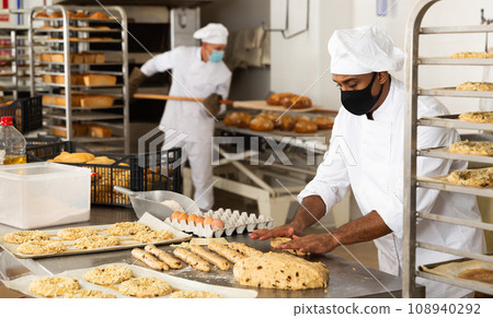 man in chefs uniform kneading dough in bakery during quarantine man in chefs uniform kneading dough in bakery during quarantine 108940292