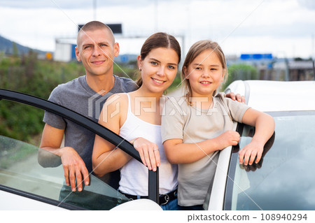 Positive family standing near an open car Positive family standing near an open car 108940294