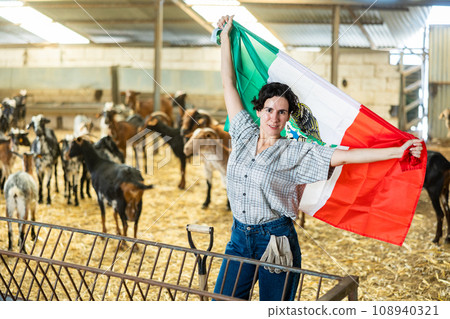 Portrait of female farmer with Mexican flag in their hands in goat pen at farm Portrait of female farmer with Mexican flag in their hands in goat pen at farm 108940321