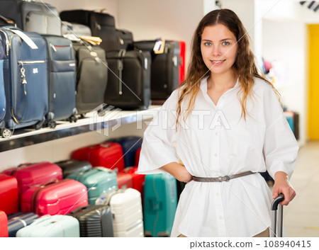 Portrait of a positive young girl in a shop with a travel suitcase 108940415