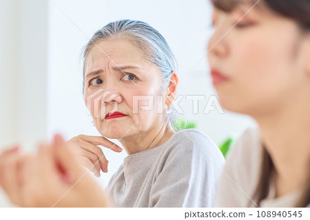 一位老婦人表情嚴峻地看著一位年輕女子 108940545
