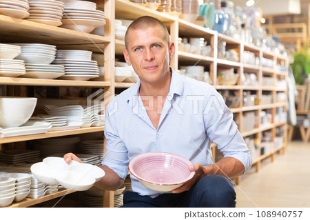 Ordinary male buyer chooses plates in store closeup 108940757