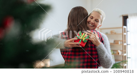 Thankful Caucasian woman with christmas gift hugging daughter at home 108940818
