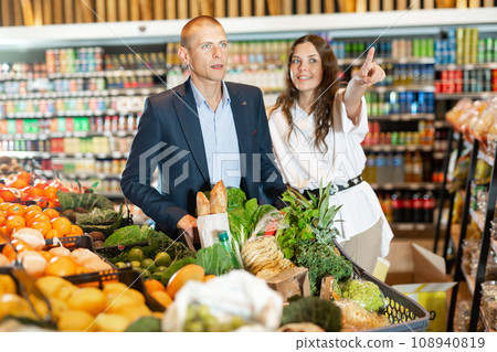 Portrait of a happy young couple in a supermarket with a full grocery cart 108940819