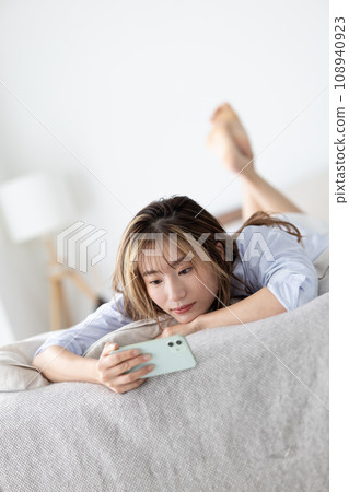 Beauty: A woman lying on the bed and looking at her smartphone 108940923