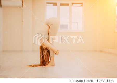 Young sporty woman, fitness instructor in sportswear doing stretching and pilates on yoga mat in the studio with mirror. Female fitness yoga routine concept. Healthy lifestyle and harmony. Young sporty woman, fitness instructor in sportswear doing stretching and pilates on yoga mat in the studio with mirror. Female fitness yoga routine concept. Healthy lifestyle and harmony. 108941170