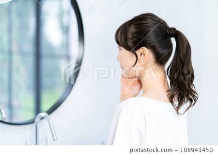 一位女士在鏡子前檢查自己的皮膚。 一位女士在鏡子前檢查自己的皮膚。 108941450