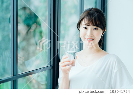 一名婦女早上在窗邊喝水。 108941734