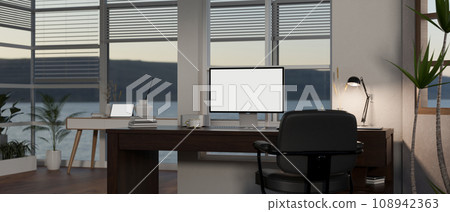 A modern private office workspace with a white-screen computer mockup on a table against the window. 108942363