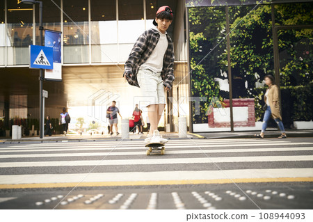 15-year-old asian teenager boy skateboarding outdoors in the street 15-year-old asian teenager boy skateboarding outdoors in the street 108944093