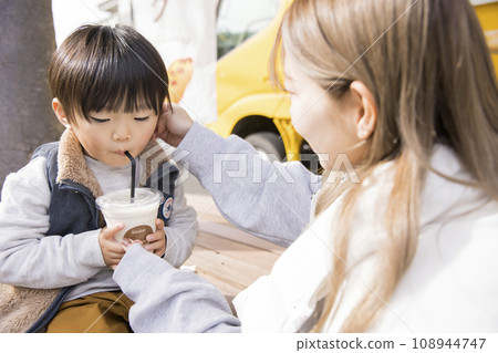 Parent and child drinking banana juice bought from a kitchen truck 108944747