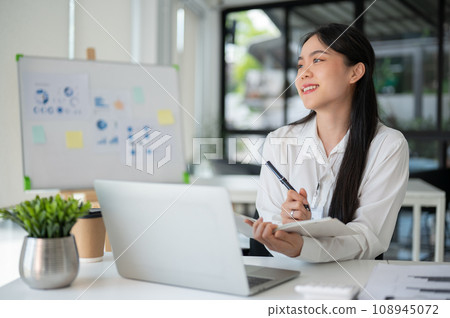 Young beautiful Asian businesswoman working for her client in her office room with laptop and office supplies. Young beautiful Asian businesswoman working for her client in her office room with laptop and office supplies. 108945072