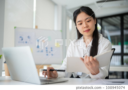Young beautiful Asian businesswoman working for her client in her office room with laptop and office supplies. 108945074