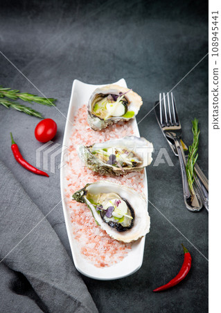 Grilled oysters on red sea salt with lime 108945441