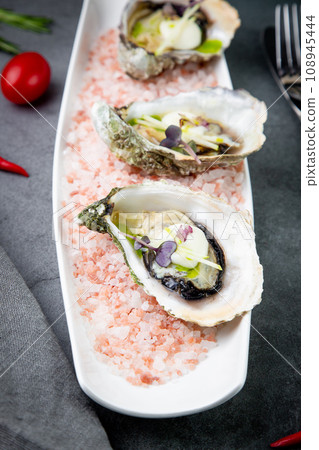 Grilled oysters on red sea salt with lime 108945444