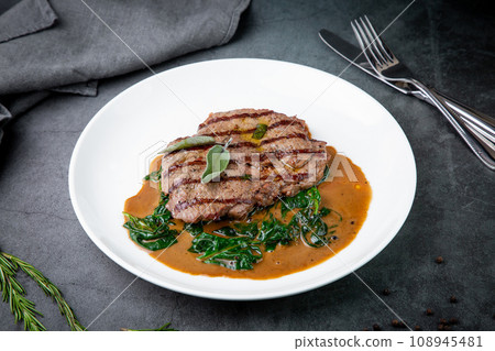 steak in gravy with herbs on it on a white plate steak in gravy with herbs on it on a white plate 108945481