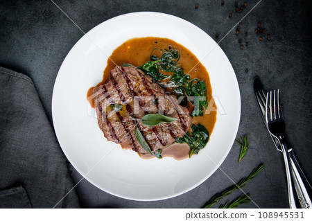 steak in gravy with herbs on it on a white plate steak in gravy with herbs on it on a white plate 108945531