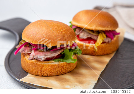 hot burgers with lettuce and vegetables on a wooden board hot burgers with lettuce and vegetables on a wooden board 108945532