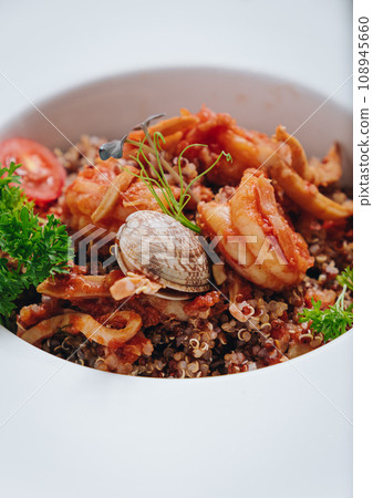buckwheat with seafood, oyster, tomato and herbs in a deep plate side view 108945660