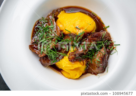mashed potatoes with meat, sauce and herbs in a deep plate side view 108945677