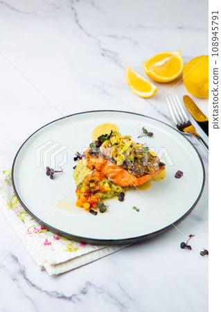 red fish with vegetable sauce and puree on a round plate side view 108945791