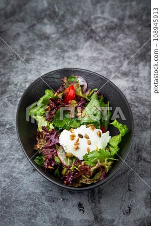 salad with lettuce, radishes, tomatoes, parsley, seeds and cheese side view salad with lettuce, radishes, tomatoes, parsley, seeds and cheese side view 108945913
