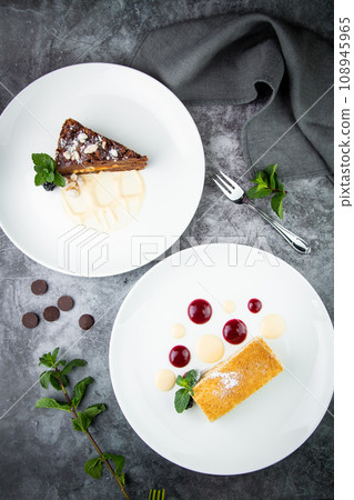 white sponge cake with drops of syrup, mint and wild berries on a round plate top veiw white sponge cake with drops of syrup, mint and wild berries on a round plate top veiw 108945965