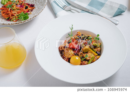 vegetable stew with potatoes, tomatoes and herbs with sauce in a deep plate side view 108945974