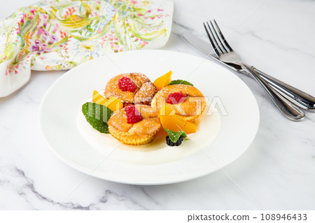 muffins with peach, raspberry, black berry and mint covered with powdered sugar, side view muffins with peach, raspberry, black berry and mint covered with powdered sugar, side view 108946433