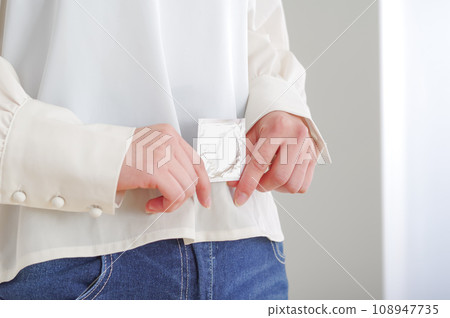 Woman's hand holding a condom 108947735