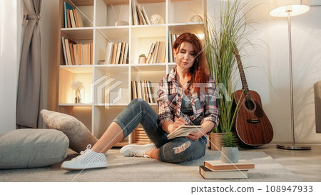 Muse inspiration. Romantic adult woman. Home leisure. Casual lady sitting floor making notes in cozy atmosphere in light room interior. 108947933
