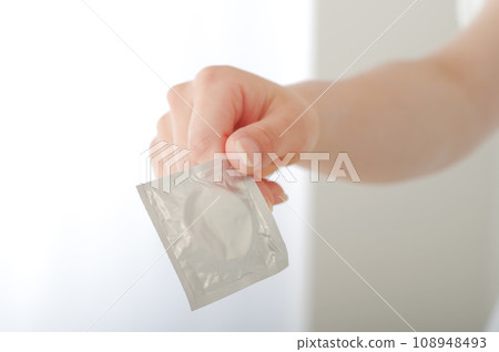 A woman's hand handing over a condom A woman's hand handing over a condom 108948493