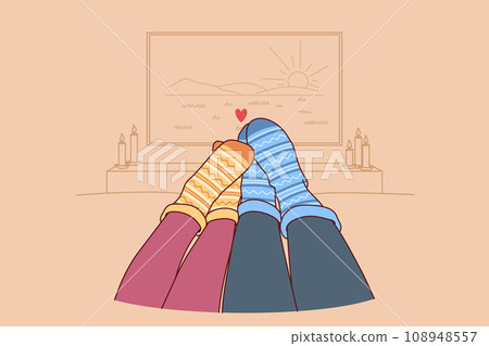 Feet of loving couple in autumn warm socks lying on sofa and watching TV in romantic home atmosphere 108948557