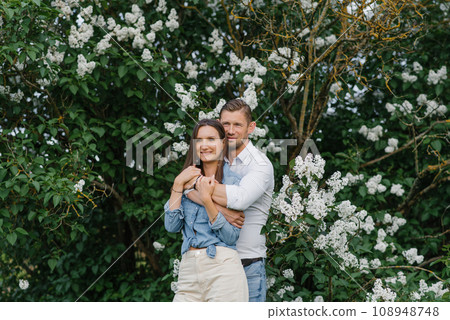 Beautiful young couple in a romantic place, spring blooming lilac garden. Happy joyful couple enjoying each other while walking in the garden 108948748