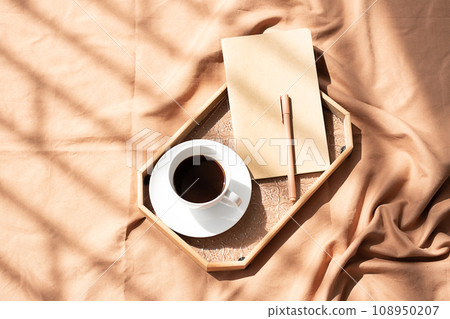 Coffee cup and notebook on bed. Cozy morning still life. 108950207
