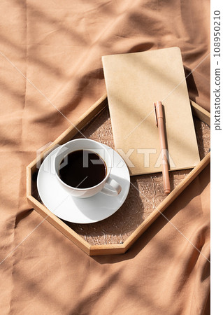 Coffee cup and notebook on bed. Cozy morning still life. 108950210