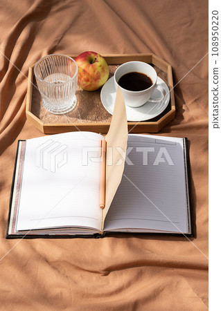 Open empty notebook and coffee cup on bed. Cozy morning at home. 108950220