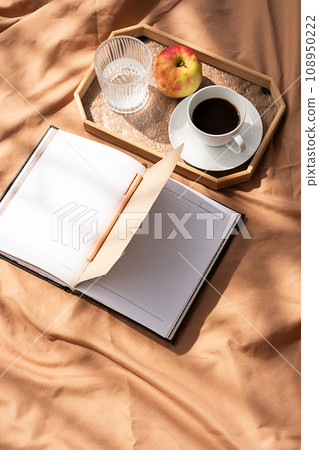 Open empty notebook and coffee cup on bed. Cozy morning at home. 108950222