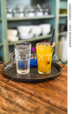Glass of passion fruit juice with glass of water with ice on a tray in the kitchen 108950904