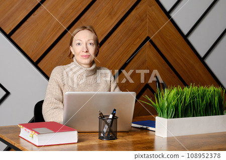 Middle aged woman sits at a table, using her laptop with wireless technology indoors 108952378